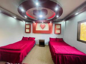 2 Betten in einem Zimmer mit roter Bettwäsche und einer Decke in der Unterkunft Bedouin Panorama House in Wadi Musa