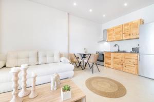 a living room with a white couch and a kitchen at SoL Suites Pefkochori in Pefkohori +58 photos
