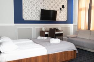 um quarto de hotel com uma cama e uma cadeira e uma televisão em Hotel Kamienica em Siedlce