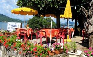 un groupe de tables et de chaises avec des fleurs et un parasol dans l'établissement Hotel Restaurant - Acacias Bellevue, à Veyrier-du-Lac