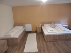 two beds in a room with wooden floors at Apartments Izvor Lisine in Strmosten