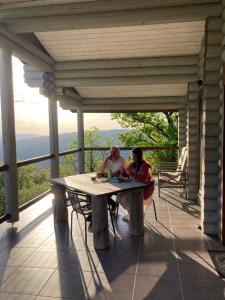カベセイラス・デ・バストにあるPrivate Mountain Log Cabin with amazing panoramic sunset views at small scale nature resortの二人のポーチのテーブルに座っている