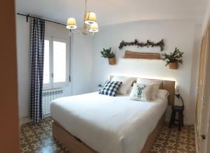 1 dormitorio con 1 cama grande con sábanas y almohadas blancas en Casa Lola - Terraza panorámica en el centro del pueblo, en Sant Joan de les Abadesses