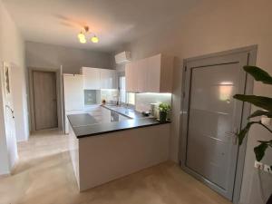 a kitchen with white cabinets and a black counter top at Evie’s Apartment in Perdika