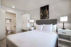 a bedroom with a large white bed and a bathroom at Soka Suites Dallas - Las Colinas in Irving