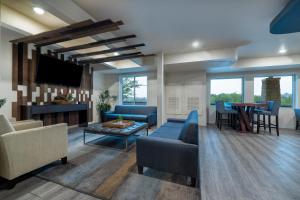 sala de estar con sofás azules y TV en Soka Suites Dallas - Las Colinas en Irving