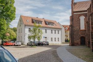 a white building with cars parked in a parking lot at Ferienwohnung an der Kirche in Spremberg