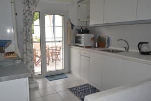 a white kitchen with a sink and a microwave at Summer Family House with sea view and garden in Kriopigi +6 photos