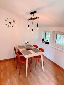 a dining room table with red chairs and a clock on the wall at Cozy House Didi 