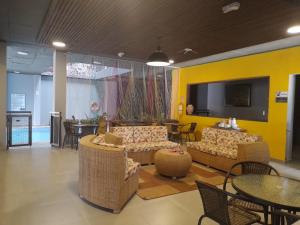 un salon avec des canapés et des tables et un mur jaune dans l'établissement Hotel Tepuy, à San José del Guaviare