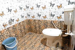 a bathroom with a toilet with butterflies on the wall at Isiri river side stay in Kalasa