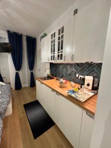 a kitchen with white cabinets and a wooden counter top at Due Mari Suites - Fiera Milano & Portello in Milan +39 photos