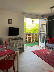 ein Wohnzimmer mit einem Tisch, einem TV und einem Balkon in der Unterkunft Appartement Résidence Saint Jours - Centre ville in Vieux-Boucau-les-Bains