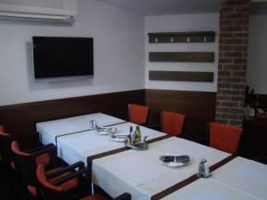 a dining room with two tables and a flat screen tv at Penzion Royal in Trenčín