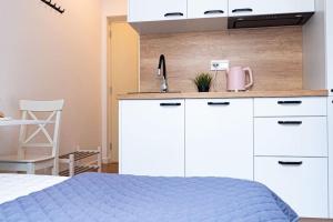 ワルシャワにあるMini kawalerka w samym Centrum Warszawyのキッチン(白いキャビネット、青いベッド付) +12枚の写真