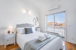 a white bedroom with a bed and a large window at GuestReady - Gold Leaf in Porto