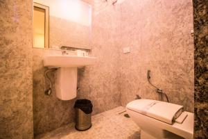 uma casa de banho com um lavatório, um WC e um espelho. em Capital O 5764 A Park Hotel em Gwalior