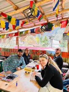 un gruppo di persone seduti a un tavolo con bandiere di Hostel 360 Degree a Manāli