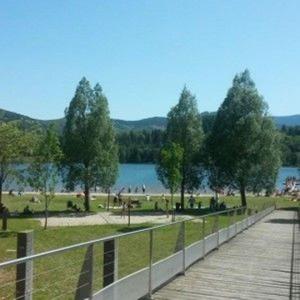 a wooden boardwalk next to a park with trees and a lake at GÎTE EN FAMILLE EN PLEINE NATURE -Regard sur le Mézenc in Chaudeyrolles +6 photos