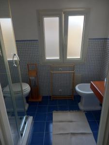 a bathroom with a toilet and a sink and two windows at 99 Scalini in Naples