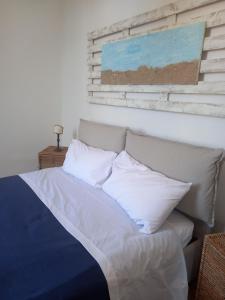 a bed with white pillows and a painting on the wall at 99 Scalini in Naples