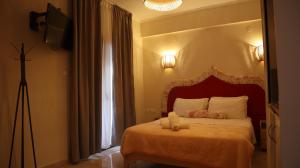 - une chambre avec un lit doté d'une tête de lit rouge et d'une fenêtre dans l'établissement Hotel Viky, à Sarti
