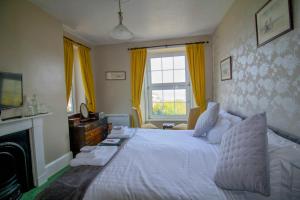 a bedroom with a white bed and a fireplace at Sinai House in Lynton