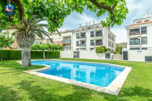 a swimming pool in a yard with a palm tree at Apartamentos San Benet Casa Azahar in Alcossebre