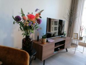 a vase of flowers sitting on a tv stand at O'Sea Bartine - private parking space & close to the beach in Ostend