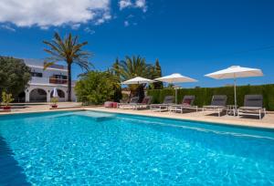 a swimming pool with chairs and umbrellas at Finca de la Pansa in Benissa