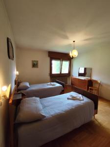 a room with three beds and a desk and a television at Panorama mozzafiato in Cortina dʼAmpezzo