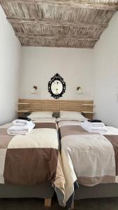 two beds in a room with a clock on the wall at Vougli View Mykonos in Drafaki