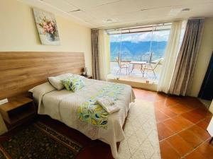 a bedroom with a bed and a balcony with a table at Hostería Paradero Yunguilla in Santa Isabel