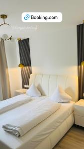 Cama blanca con sábanas y almohadas blancas en Ferienhaus Doina, en Gehlberg