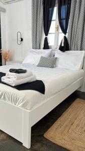uma cama branca com almofadas pretas e brancas em Vougli View Mykonos em Drafaki