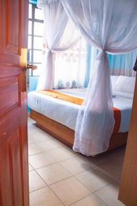 a bedroom with a bed with a canopy and a window at TROTTERS B&B KENOL in Gitura