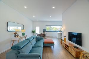 ein Wohnzimmer mit einer blauen Couch und einem Fernseher in der Unterkunft Xª Deluxe Apartments in Ribeira Grande