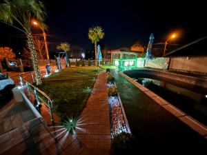 a walkway with palm trees and a bridge at night at Casa Anisia by Hypnotic in Piteşti