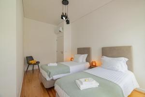 2 Betten in einem Zimmer mit weißer und grüner Bettwäsche in der Unterkunft Xª Deluxe Apartments in Ribeira Grande