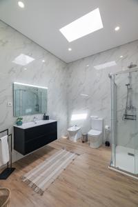 ein Badezimmer mit Waschbecken, Toilette und Spiegel in der Unterkunft Xª Deluxe Apartments in Ribeira Grande + 20 Fotos