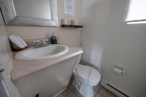 a white bathroom with a sink and a toilet at Motel Deblois in Sainte-Anne-de-Beaupré