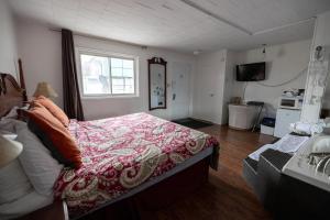 a bedroom with a bed and a window and a kitchen at Motel Deblois in Sainte-Anne-de-Beaupré