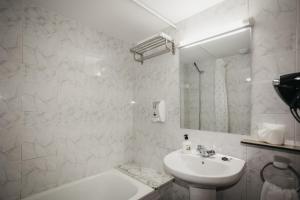 Baño blanco con lavabo y espejo en La Trobada Hotel Sport en Ripoll
