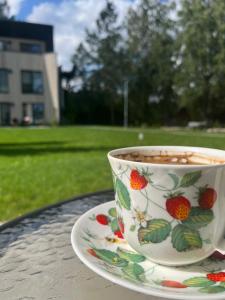 een kopje koffie zittend op een bord op een tafel bij Piejūras apartaments in Ķesterciems