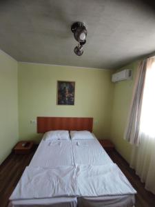 una camera da letto con un letto con lenzuola bianche e una finestra di Вила Никови a Durankulak