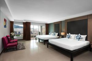 1 dormitorio con 2 camas y silla roja en Casa Del M Phuket en Patong Beach