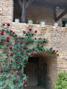 eine Steinmauer mit roten Rosen, die darauf wachsen in der Unterkunft Gîte à la ferme in Viserny
