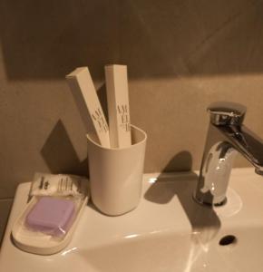un lavandino da bagno con una tazza con spazzolini da denti di Lauda i bric a Mirna