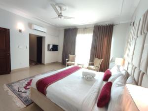 ein Schlafzimmer mit einem großen weißen Bett mit roten Kissen in der Unterkunft Margalla Hills Residency Islamabad Guest House in Islamabad