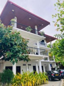 Hotel Siyathma polonnaruwa في بولوناروا: مبنى أبيض مع شرفة وسيارات متوقفة في الأمام